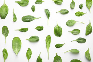 Fresh green healthy spinach leaves with water drops on white background, top view