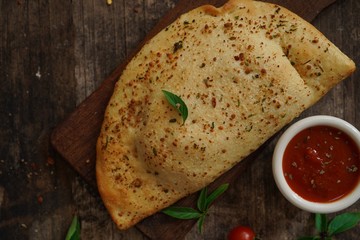 Calzone - Italian folded CheesePizza on rustic wooden background