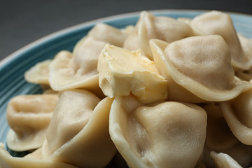 Tasty dumplings with butter on blue plate, closeup