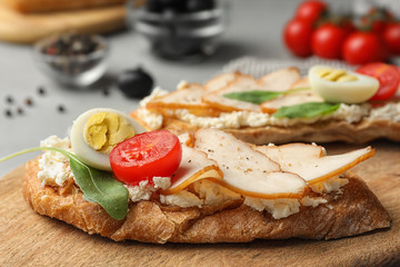 Board with delicious chicken bruschettas on table, closeup