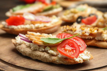 Delicious chicken bruschettas on wooden board, closeup