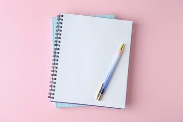 Notebooks and pen on pink background, top view