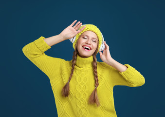 Young woman listening to music with headphones on dark blue background