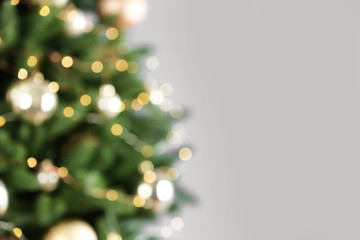 Beautiful Christmas tree with lights against grey background, blurred view. Space for text