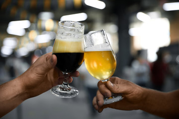 Men with glasses of light and dark beer in bar, closeup