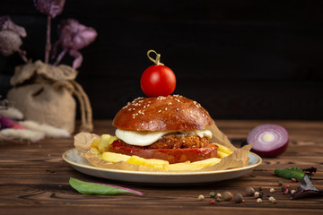 cheeseburger decorated with cherry tomato on a plate on a wooden table © Said Ramazanov