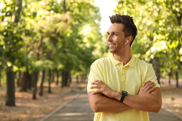 Young man with wireless earphones in park