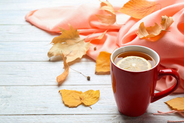 Naklejka na ściany i meble Cup of hot drink and leaves on white wooden table, space for text. Cozy autumn atmosphere
