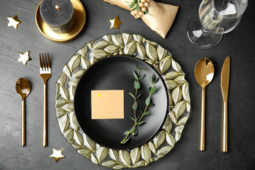 Elegant festive table setting with blank card on black background, flat lay