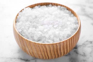 Bowl with white sea salt on marble table, closeup. Spa treatment