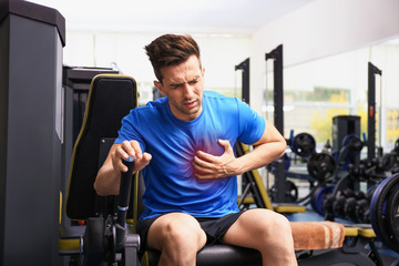 Young man having heart attack in gym - obrazy, fototapety, plakaty