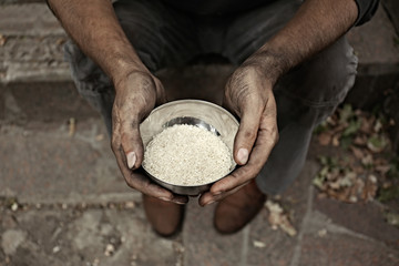 Poor homeless man with bowl of rice outdoors, closeup