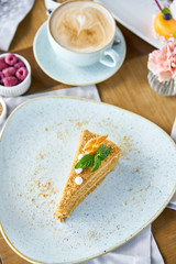 Honey sponge cake decorated with meringue and mint leaves.. Breakfast in the cafe, morning coffee. Cappuccino and lots of desserts on the table.