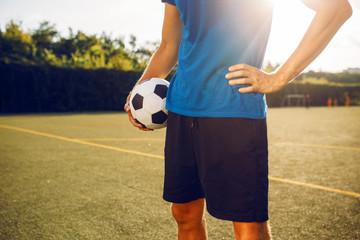 Male soccer player with ball standing on the field