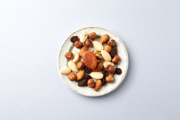 Nuts, raisins and apricots on bright paper background. Concept for healthy snack. Top view. Copy space. 