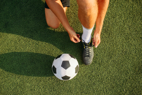 Male soccer player ties his shoelaces on boots