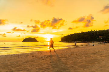 tourists playing frisbee on the beach in golden sunset time at Kata beach Phuket Thailand.