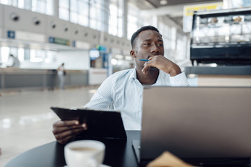 Ebony businessman at laptop in car dealership