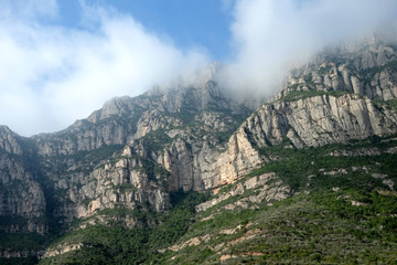 Rocky mountains and clouds at sunny spring day near Montserrat Abbey, Barcelona Catalonia, Spain.