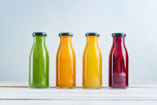 Green, yellow, orange and red smoothie in glass bottles