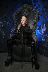 Photo of a female witch queen holding bird and sitting on a gothic scary black throne