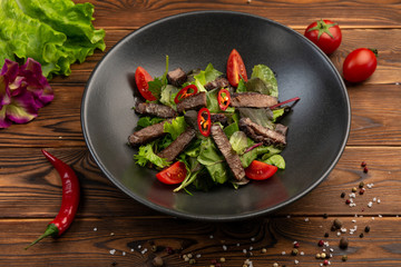 Thai beef salad of baked veal tenderloin, salad mix, cherry, chili pepper with olive oil