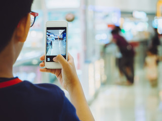 Hand kid person using smartphone or cellphone take a photo in shopping mall. Shopping mall most...