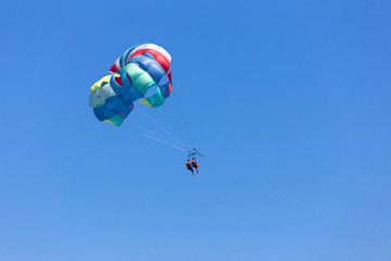 Two people parasailing in a blue sky