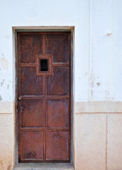Rusty metal door in a niche of a front wall.