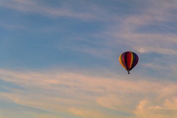 Rainbow hot-air balloon isolated in colorful clouds at sunrise
