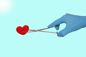 hand in a blue glove holds a stethoscope red heart isolated on a blue background, surgeon doctors save lives, toned
