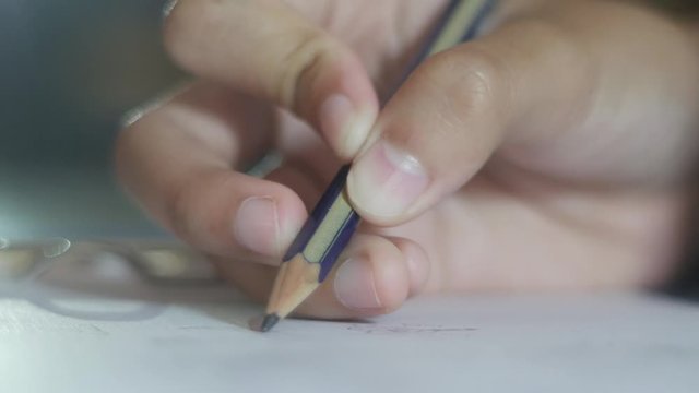 Close up image of little girl's hand drawing with pencil on paper, making doodle sketch art
