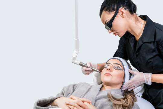 Beauty laser technician performing a cosmetic skin resurfacing session on a female patient, also called a laser peel  or photofacial, with an Er:Yag laser (infrared wavelength).