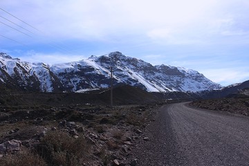 country road in a valley between the mountains with snow in Chile