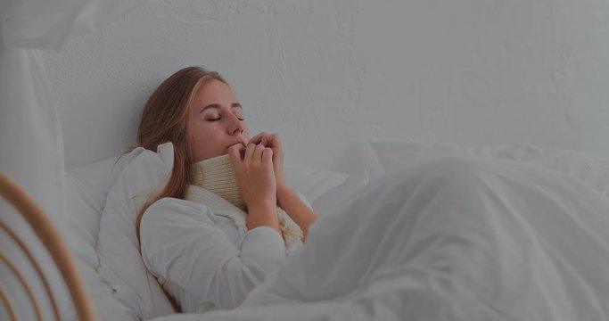 Girl is sick, she lies in bed in a scarf. Portrait view.