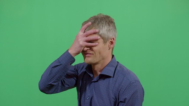Adult Man Slapping His Forehead Suggesting Bad News Notice. Studio Isolated Shot Against Green Screen Background