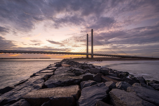 Bridge and Jetty at Sunset on a Calm Evening at the Beach with Orange Sky with Clouds