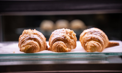 three croissant sprinkled with powdered sugar in cafe shop.