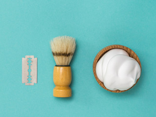 Shaving brush and shaving foam in a wooden bowl. Flat lay.