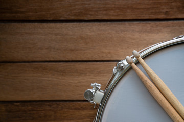 close up drum stick and drum on wooden table background, top view, music concept