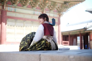 Portrait Asian women wearing hanbok sitting and facing to the side in Gyeongbokgung palace in Seoul, South Korea