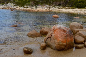 An orange tinted rock in a tranquil cove at the Bay of Fires in NE Tasmania.