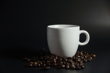 white cup with coffee beans in dark light