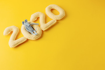 Happy New year concept. 2020 knitted yallow numbers with the symbol of the year the rat on a yellow background. Seasonal funny decoration, holiday symbol, party, monochrome