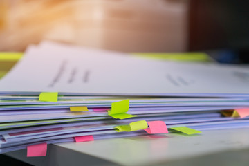 Fototapeta premium Stack of overwork of document report with post-it in business busy concept: Piles of paper files with postit on paperwork in overload at modern office