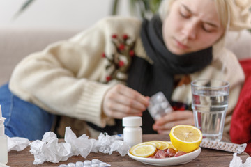 The girl in the sweater is sick lying on the couch. Colds and flu. The patient caught a cold,...