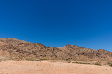 Bright blue sky without clouds and desert land and mountains at the botton. negative  blue space for text
