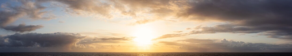Dramatic Panoramic View of a cloudscape during a dark, rainy and colorful sunset. Taken on the Ocean Coast of Alaska, USA.