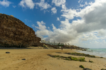 a fantastic beach with rocks and a big house in the background - 295574976