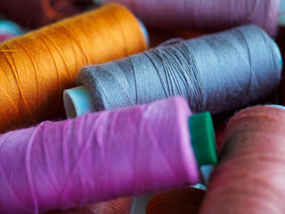 Lots of bobbins of thread for sewing. Threads of different colors.